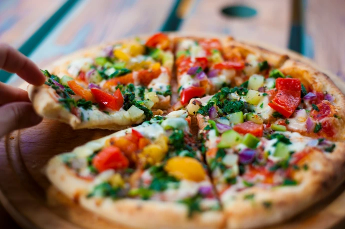 pizza with green and red bell pepper and cheese on brown wooden table
